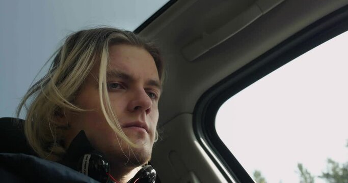 Low angle view of a man passenger inside car. Stock. Man with blond dyed hair looking worried and focused.