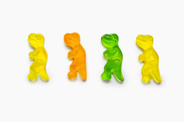 Four multi-colored dinosaur shaped gummy candies on a white background. Colorful sweet...