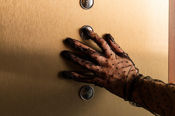 Close-up of a hand in a Mesh Sheer glove of an elegant girl pressing a button in an elevator. Concept of elegance and sophistication. Formal or upscale event.