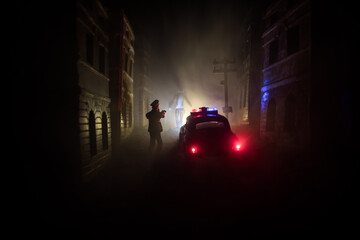 Police raid at night and you are under arrest concept. Silhouette of handcuffs with police car on backside. Image with the flashing red and blue police lights at foggy background. Slider shot © zef art
