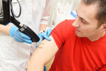 Obraz premium cosmetologist uses a CO2 fractional ablative laser to rejuvenate the skin and remove scars to a male patient in a modern cosmetic beauty clinic.