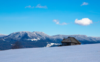 A beautiful landscape of an old abandoned wooden house on a mountain in winter
