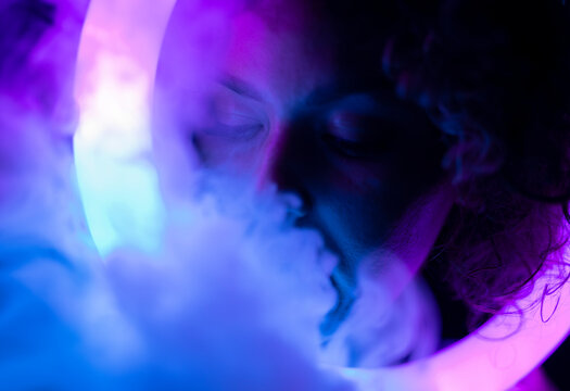 Blurred portrait of woman with a smoke in neon light