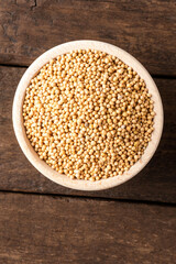 White mustard seeds in bowl on wooden table. Close up. Top view