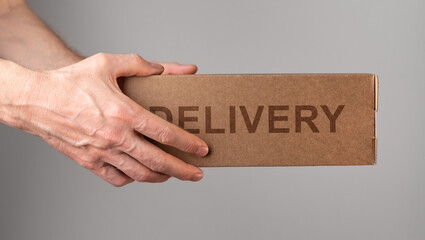 Couriers hands holding cardboard box, delivering order, postal parcel in brown package side view