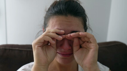 Fototapeta premium One sad tearful woman crying. Portrait of a depressed person close up face in tears. Real life authentic emotion