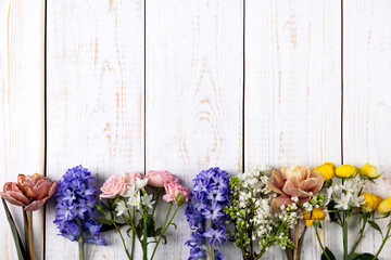 Fototapeta na wymiar Bright spring composition of daffodils, hyacinths, roses, tulips, lilac on a white wooden background. Hello spring. Happy birthday, happy Women's Day, happy wedding