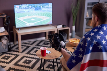 Side view of sports fan watching baseball match at home on TV and wearing USA flag, copy space