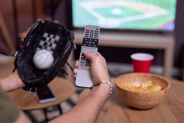 Close up of baseball fan holding TV revpmte while watching match at home, copy space