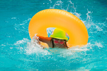 Summer fun kids face. Child splashing and swimming on inflatable toy ring in pool. Swim water sport activity on summer vacation with child.