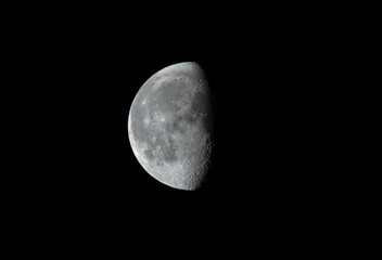 Third quarter moon in the night sky showing crater detail