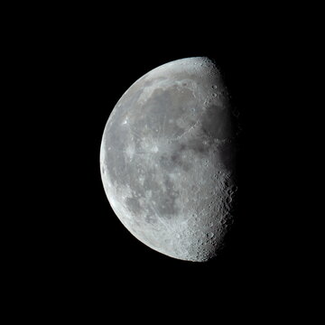 Third quarter moon in the night sky showing crater detail