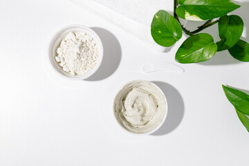 White bowls with white cosmetic clay on white table - mineral powder, bentonite facial mask. Skincare beauty concept.