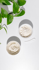White bowls with white cosmetic clay on white table - mineral powder, bentonite facial mask. Skincare beauty concept.