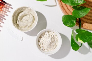 White bowls with white cosmetic clay on white table - mineral powder, bentonite facial mask. Skincare beauty concept.