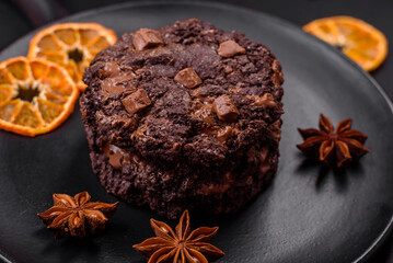 Delicious fresh oatmeal round cookies with chocolate on a black ceramic plate
