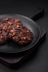 Delicious fresh oatmeal round cookies with chocolate on a black ceramic plate