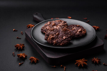 Delicious fresh oatmeal round cookies with chocolate on a black ceramic plate