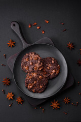 Delicious fresh oatmeal round cookies with chocolate on a black ceramic plate