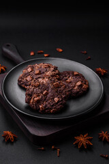 Delicious fresh oatmeal round cookies with chocolate on a black ceramic plate