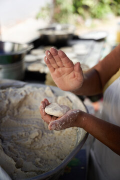 Unrecognizable elderly woman preparing corn tortillas by hand on a griddle in her modest street kitchen