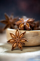Fototapeta na wymiar Anise stars (Illicium verum ) in wooden bowl on dark rustic wooden background. Favorite spice in many food and use for medicine. Fragrant Asian spice and Herb concept.
