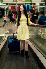 a girl with her blue suitcase and dressed in yellow at the station