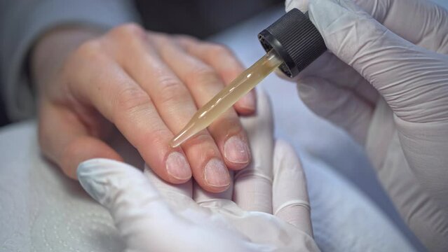 Manicurist applies cuticle oil to her client