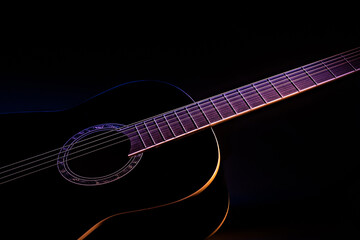 Fototapeta na wymiar fragment of a black guitar against a dark background. guitar music low-key concept side view