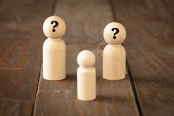 Orphan thinking about "who are my real parents?" adoption concept. Wooden figures simulate orphan or foster son questioning yourself about your parents and emotional problems on brown wood surface.