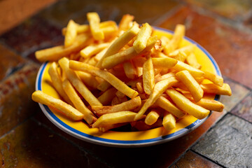 Freshly cooked french fries on plate on stone background.