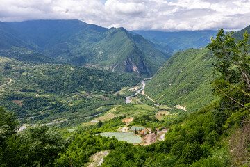 Fototapeta na wymiar Tskhenistsqali river valley landscape in Racha region of Georgia with Svaneti mountain range, lush green forests and vineyards seen from to Khvamli Mountain.