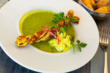 Vegetable courgette cream soup with breadstick served in white plate