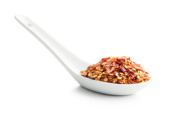 Dry chili pepper flakes in ceramic spoon. Crushed red peppers isolated on white background.