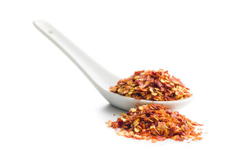 Dry chili pepper flakes in ceramic spoon. Crushed red peppers isolated on white background.