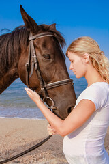 Happy pregnant woman with a horse on the beach in the summer on the nature
