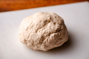 Fototapeta na wymiar Ball of cooked dough on white cutting board. Cooked dough for bread or pizza.