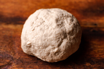 Fototapeta na wymiar Yeast dough ball on wooden background. Cooked dough for baking pizza or bread.