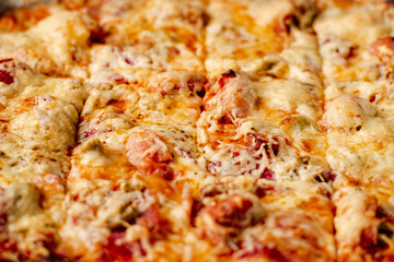 Cooked homemade pizza on baking sheet. Pizza with cheese, tomatoes, ham on baking sheet.