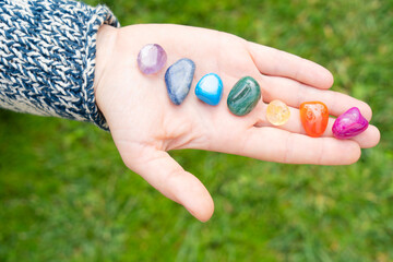 Hand holding set of chakra stones. Magic healing Rock for Reiki Crystal Ritual, Witchcraft,...
