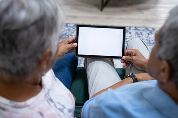 High angle view of biracial senior couple using digital tablet while relaxing at home, copy space