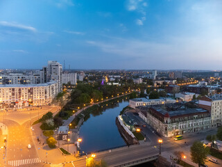 Aerial view, bridge across river Lopan, park Strilka and streets in evening illumination in spring Kharkiv, Ukraine