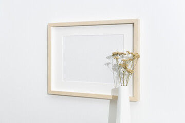 Blank wooden frame mockup on white wall with dry flowers decor