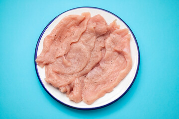 Slices of raw turkey meat fillet on white dish