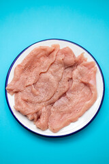 Slices of raw turkey meat fillet on white dish