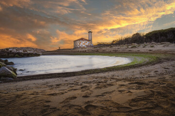 Long exposure of the lighthouse of Bibione, Venice. Crystal clear water and white rocks. Golden beach and circular shapes.