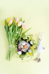 Easter scene with colored eggs in nest, bunny and handmade bunny, top view with copy space