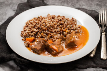 Boiled buckwheat with meat and sauce on white dish