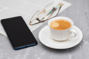 Newspapers and coffee cup, with reading glasses.