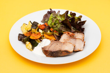 Baked pork with vegetables and fresh salad on plate